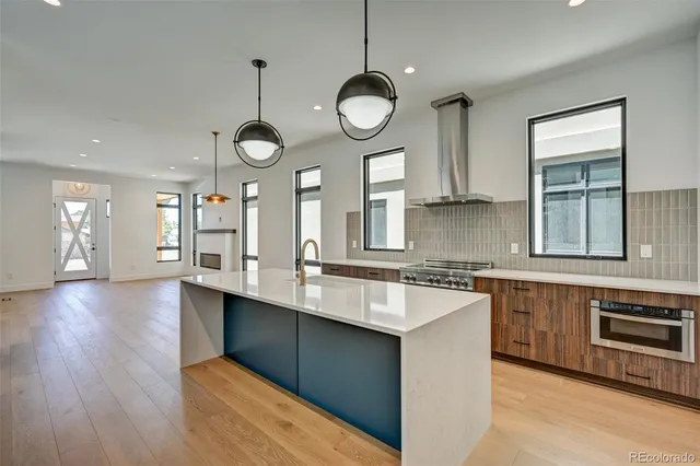 a large kitchen with stainless steel appliances a large center island attached withe living room