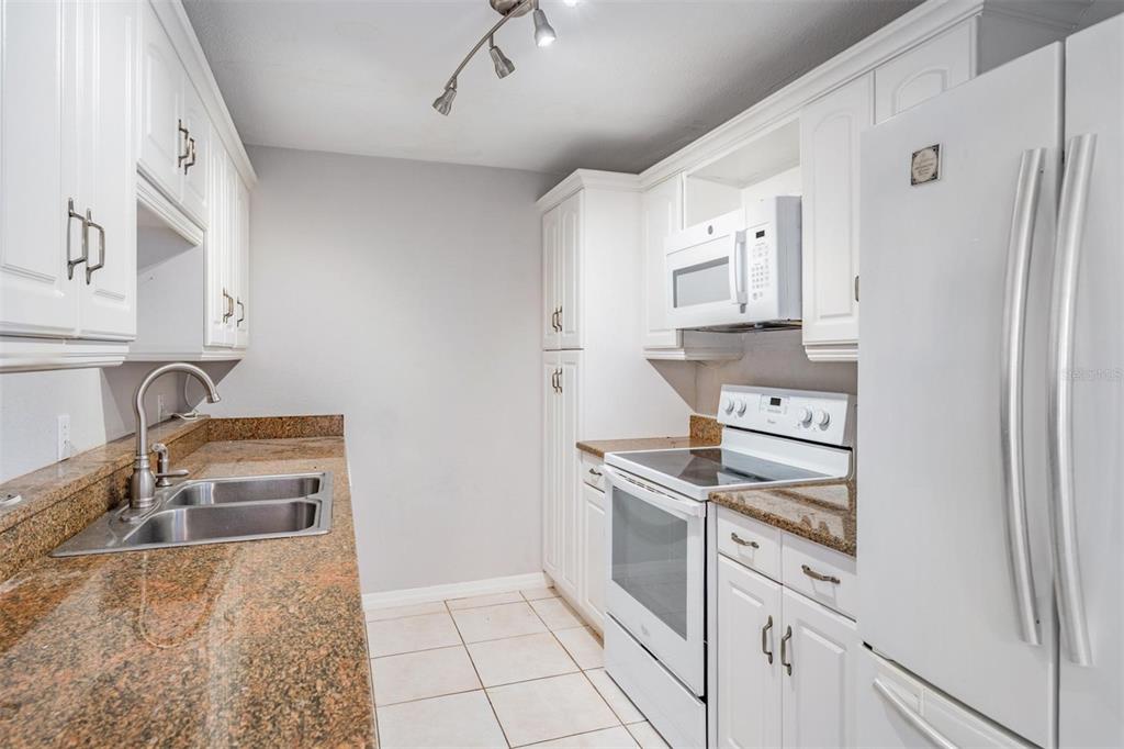 3211 West Swann Avenue, Unit 907 Tampa, FL 33609 - Photo 6 of 32 a kitchen with stainless steel appliances granite countertop a refrigerator and a sink