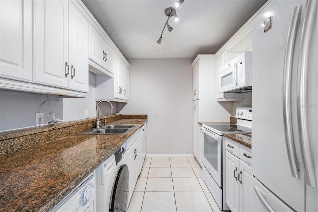3211 West Swann Avenue, Unit 907 Tampa, FL 33609 - Photo 8 of 32 a kitchen with granite countertop a sink stove and cabinets