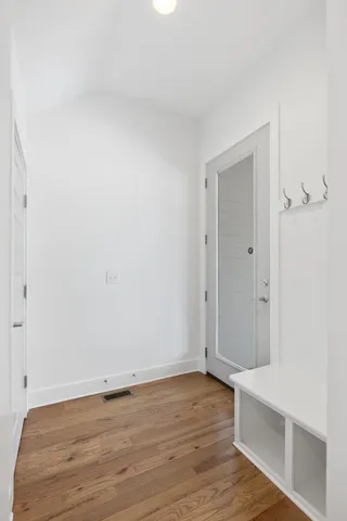 a view of an empty room with wooden floor and a window
