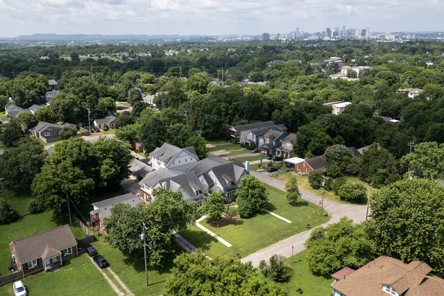 an aerial view of residential houses with outdoor space and trees