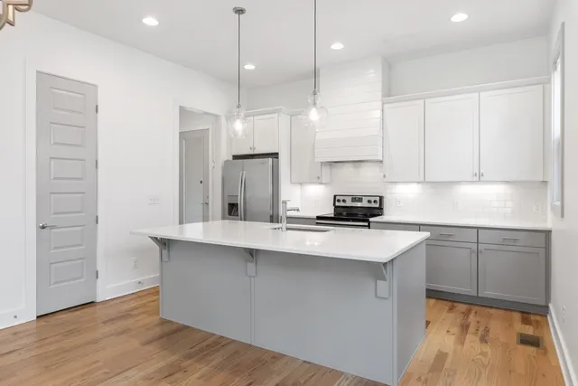 a kitchen with stainless steel appliances granite countertop a sink a stove and a refrigerator