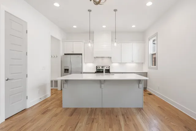 a kitchen with wooden floor white cabinets and stainless steel appliances