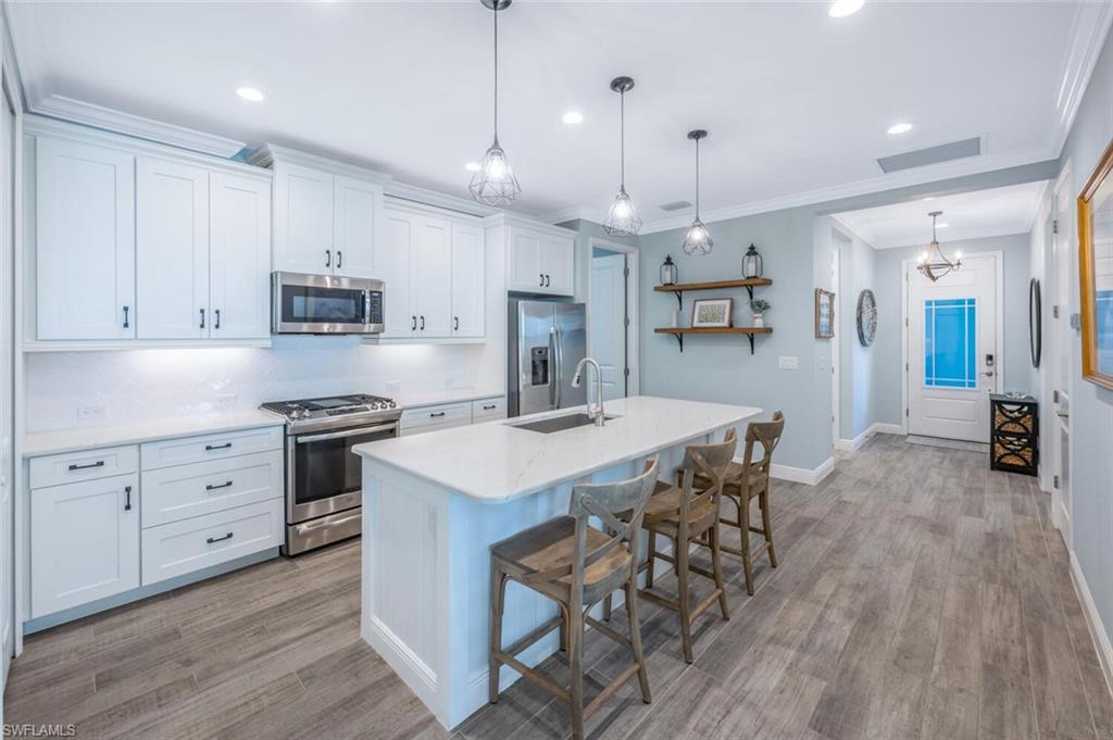 2211 Marquesa Circle Naples, FL 34112 - Photo 2 of 28 a kitchen with stainless steel appliances kitchen island granite countertop a stove a sink a refrigerator and a wooden cabinets