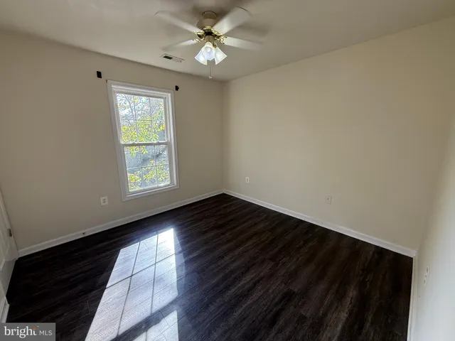 an empty room with wooden floor fan and windows