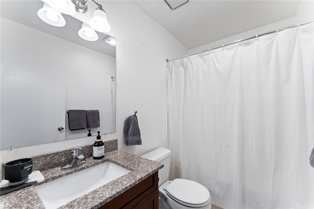 350 Burchett Street, Unit 101 Glendale, CA 91203 - Photo 17 of 27 a bathroom with a granite countertop sink vanity mirror and toilet