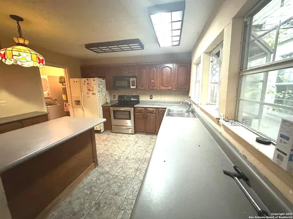 a large kitchen with kitchen island granite countertop a large window cabinets and stainless steel appliances