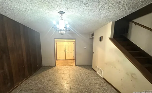 a view of a hallway with wooden floor and chandelier
