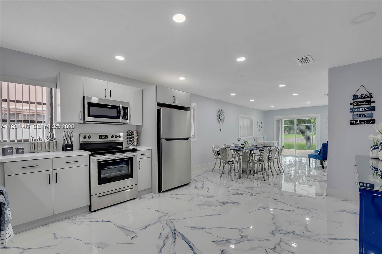 895 West 39th Place, Unit 1 Hialeah, FL 33012 - Photo 12 of 35 a kitchen with microwave a refrigerator and chairs