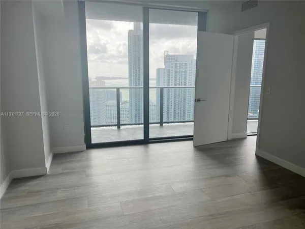 a view of an empty room with wooden floor and closet