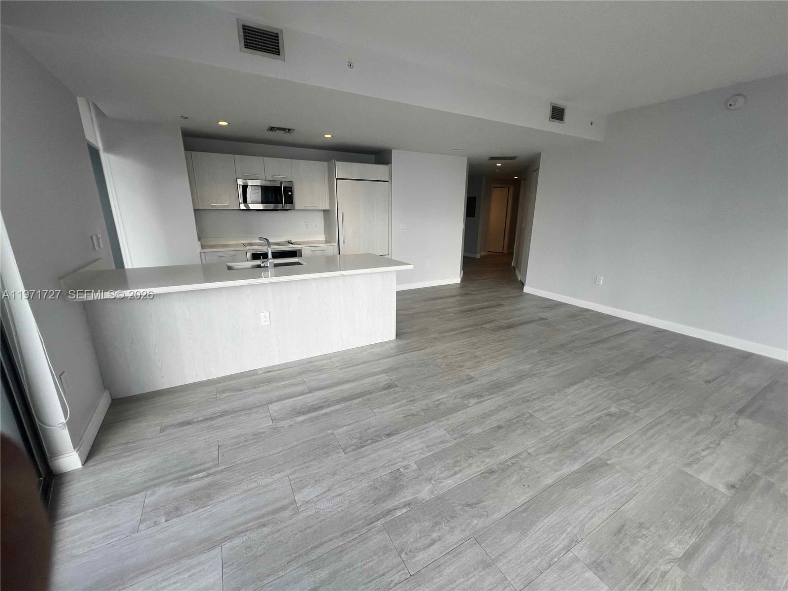 45 Southwest 9th Street, Unit 3703 Miami, FL 33130 - Photo 6 of 73 a kitchen with stainless steel appliances granite countertop a sink cabinets and wooden floor