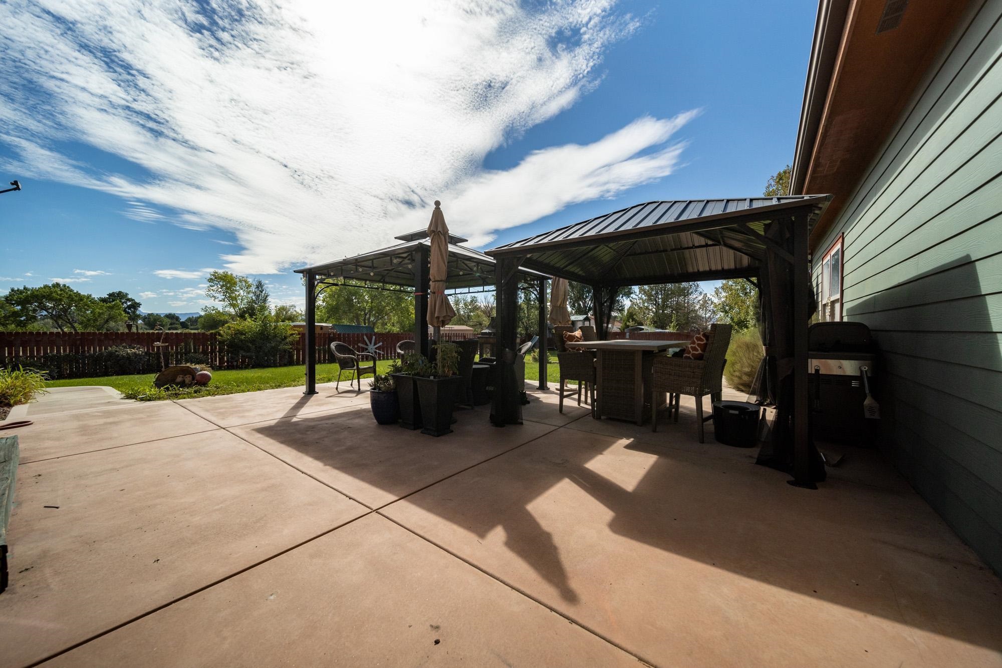 1745 North 3/10 Road Fruita, CO 81521 - Photo 34 of 41 a view of a patio with table and chairs under an umbrella with a barbeque
