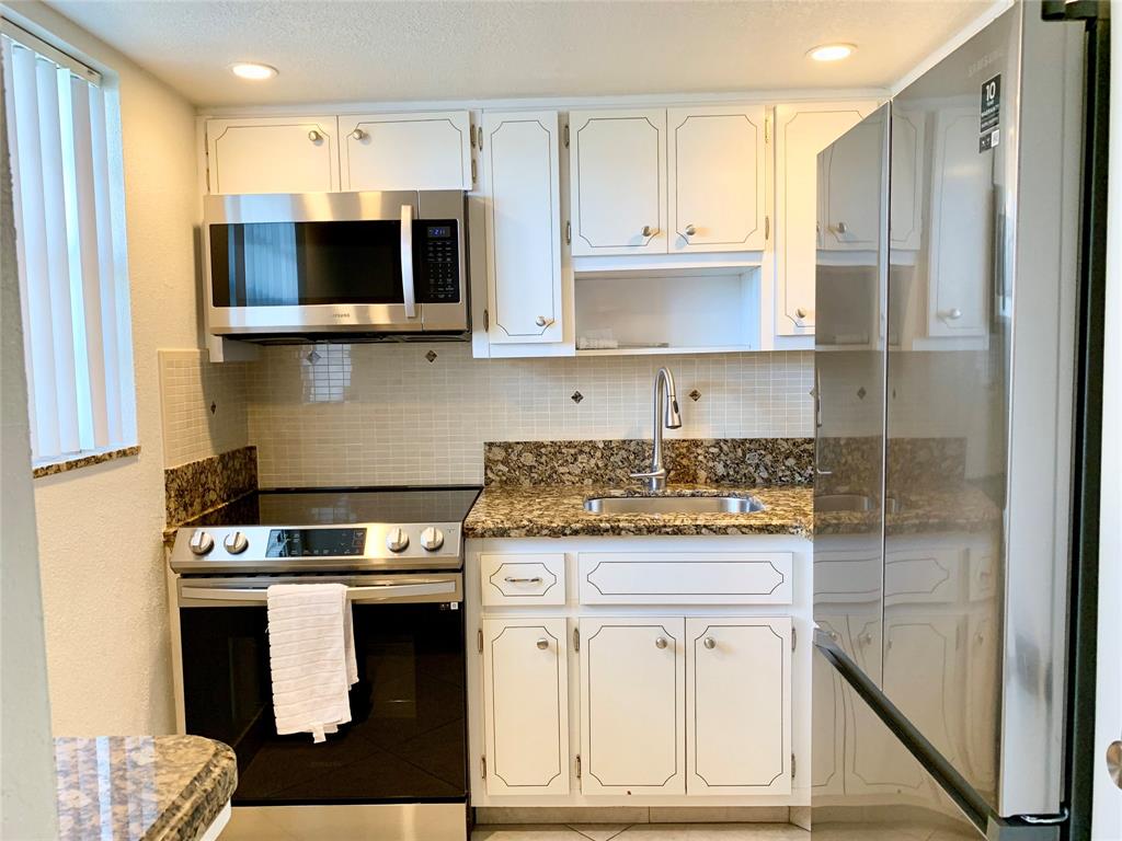a kitchen with stainless steel appliances granite countertop a stove a microwave and a refrigerator
