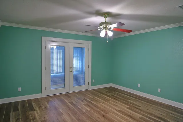 a view of an empty room with window and chandelier fan