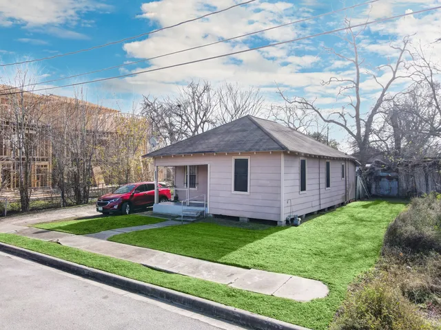 a view of a house with a yard and large trees