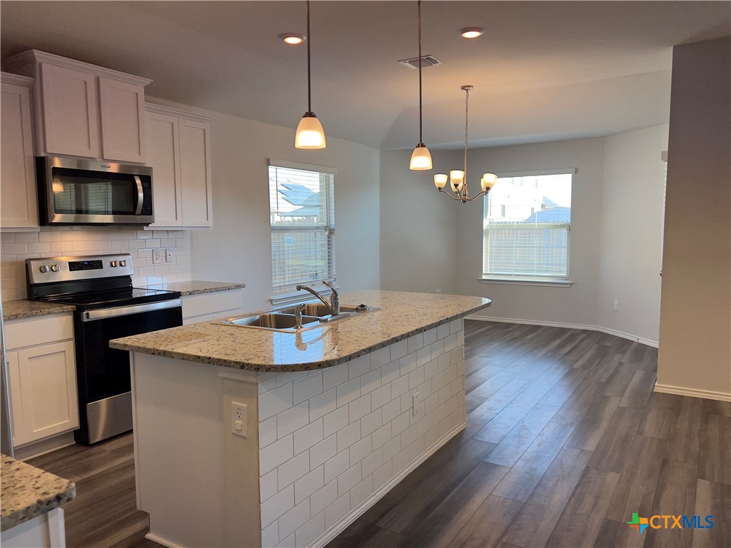 302 Saddleback Trail Killeen, TX 76542 - Photo 6 of 33 a kitchen with stainless steel appliances granite countertop a sink a microwave oven a refrigerator and white cabinets with wooden floor