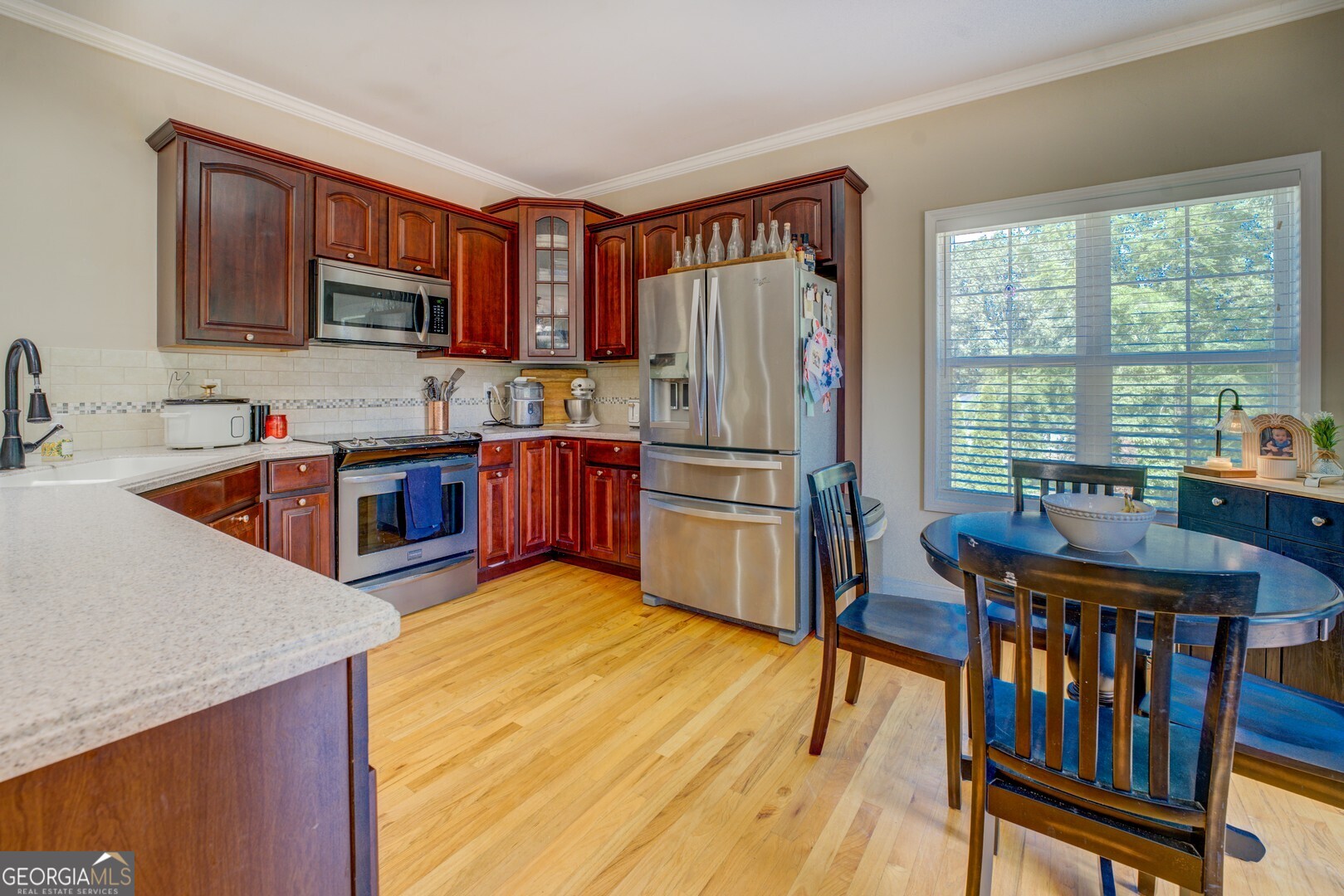 734 Raven Road Monticello, GA 31064 - Photo 37 of 81 a kitchen with stainless steel appliances granite countertop a refrigerator a sink dishwasher a stove and a dining table with wooden floor