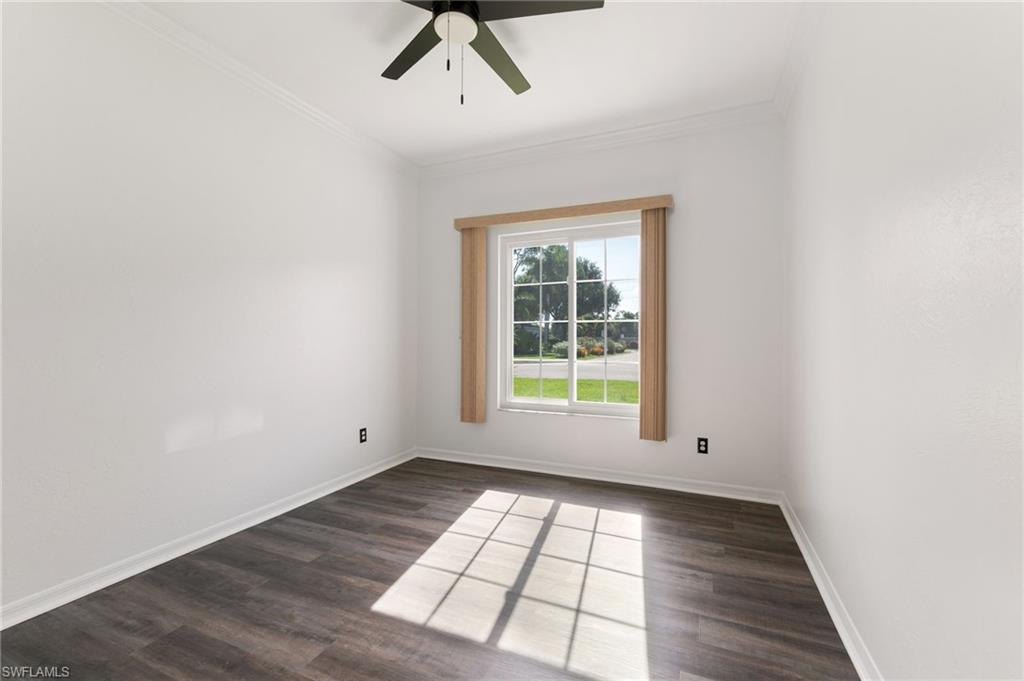 223 Stanhope Circle Naples, FL 34104 - Photo 21 of 41 Bright room featuring a large window with exterior views, dark wood-finish flooring, white walls, and a ceiling fan