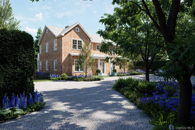 a front view of a house with a garden and a tree