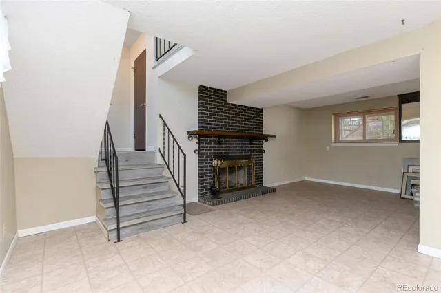 a view of an empty room with stairs and a living room