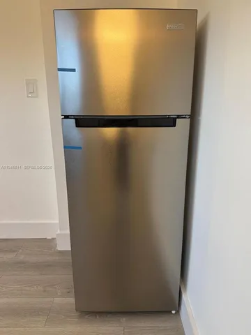 a view of an empty room with wooden floor and a ceiling fan