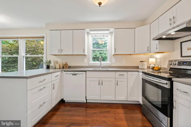 a kitchen with granite countertop white cabinets stainless steel appliances a sink and a window