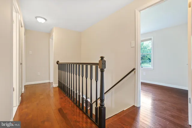a view of a hallway with wooden floor and stairs