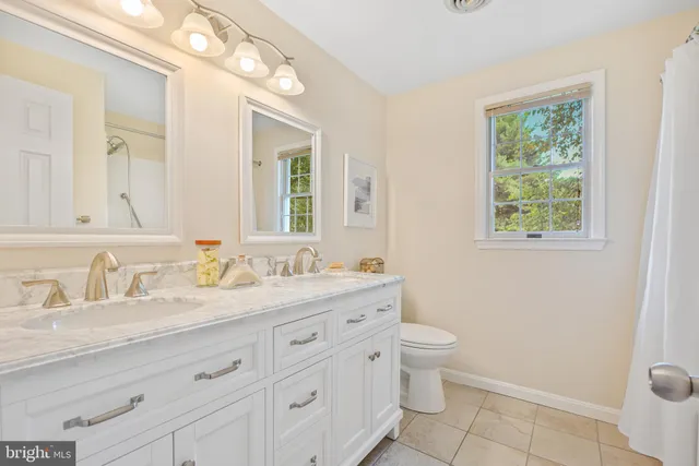 a bathroom with a granite countertop sink a toilet and a mirror