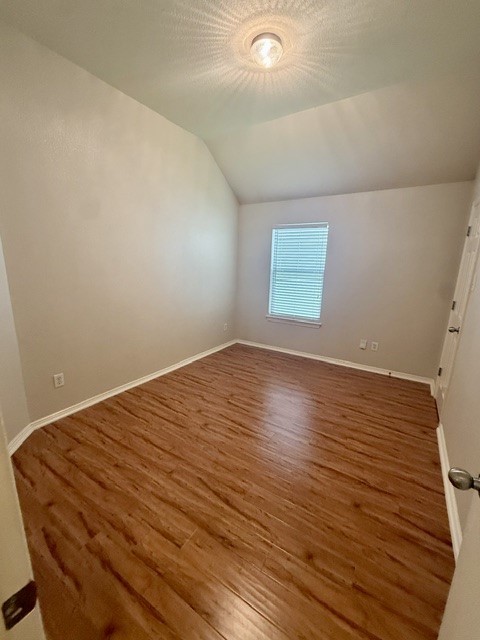 20724 Kearney Hill Road Pflugerville, TX 78660 - Photo 30 of 40 Room featuring wood-finish flooring, a vaulted ceiling, and a window with blinds