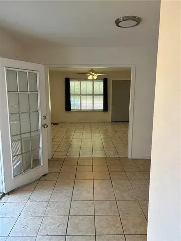 a view of an empty room and chandelier fan