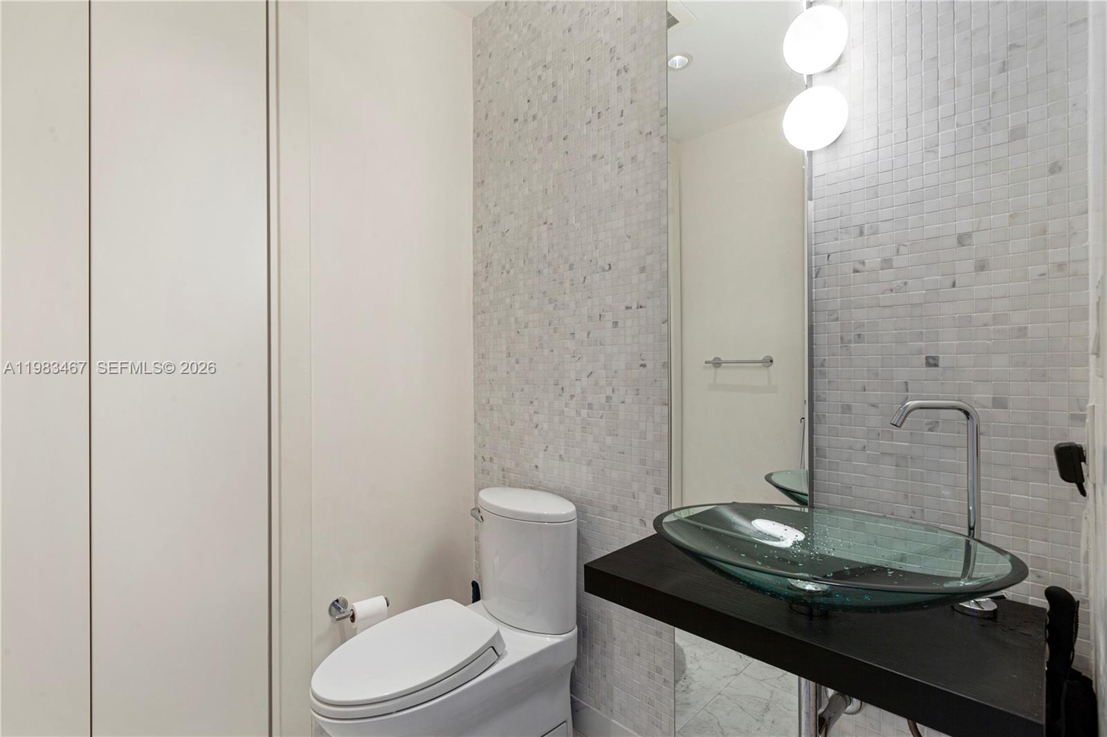 200 Biscayne Blvd Way, Unit 4907 Miami, FL 33131 - Photo 10 of 18 a bathroom with a granite countertop sink a toilet and a mirror