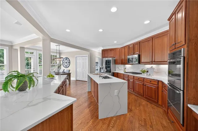 a kitchen with stainless steel appliances granite countertop a refrigerator a sink dishwasher a stove and white countertops with wooden floor