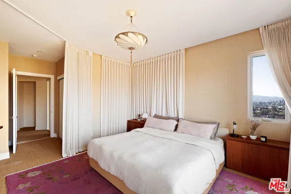 a bedroom with a bed and a dresser with wooden floor