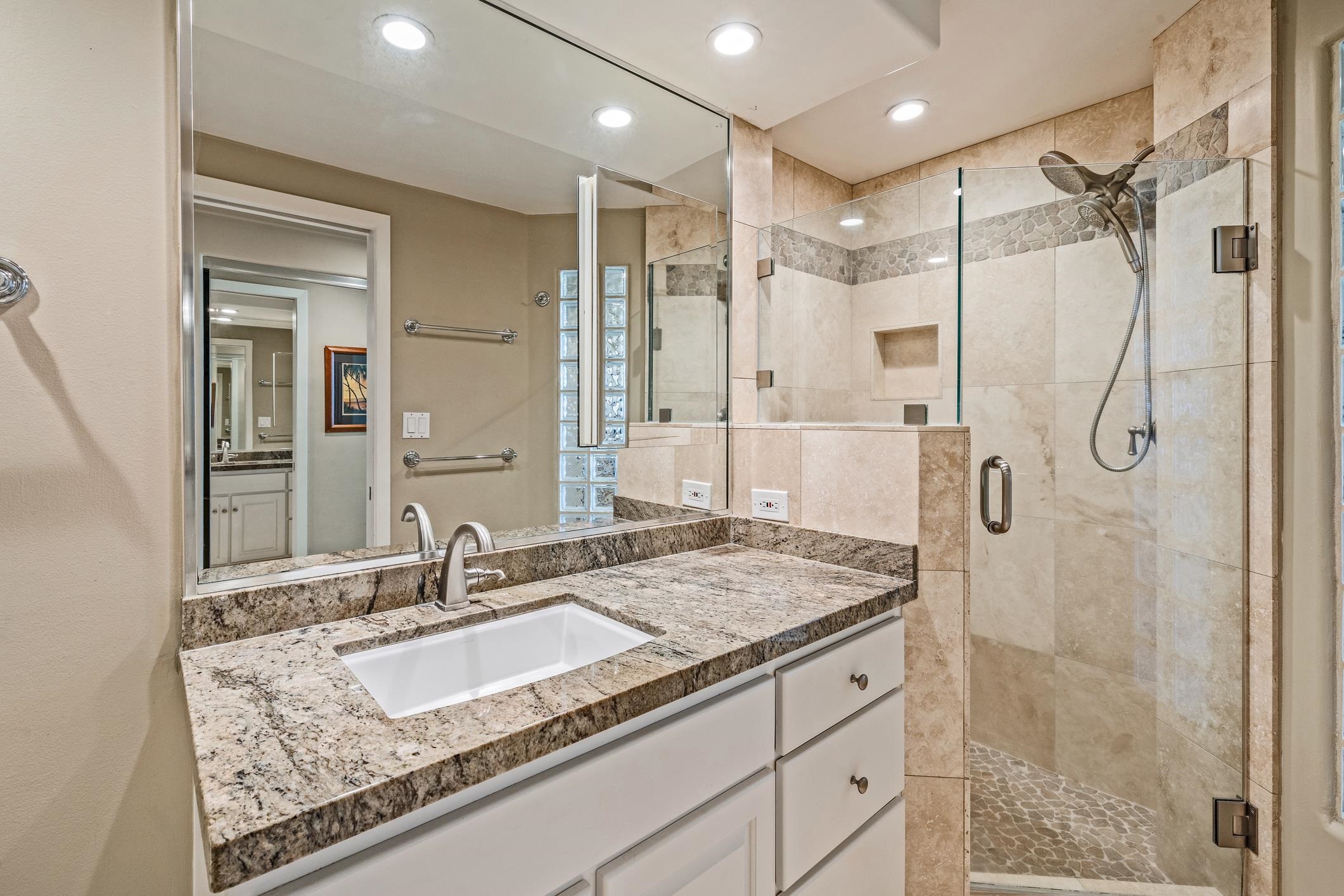 4401 Lower Honoapiilani Road, Unit A103 Lahaina, HI 96761 - Photo 37 of 45 a bathroom with a granite countertop sink a mirror a glass door a shower and vanity