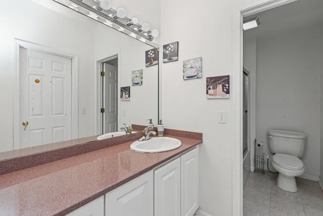 a bathroom with a granite countertop sink a toilet and a mirror
