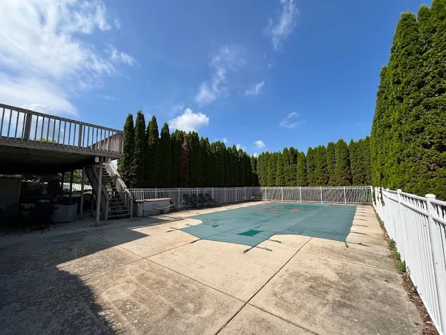a view of a swimming pool with a patio and a yard