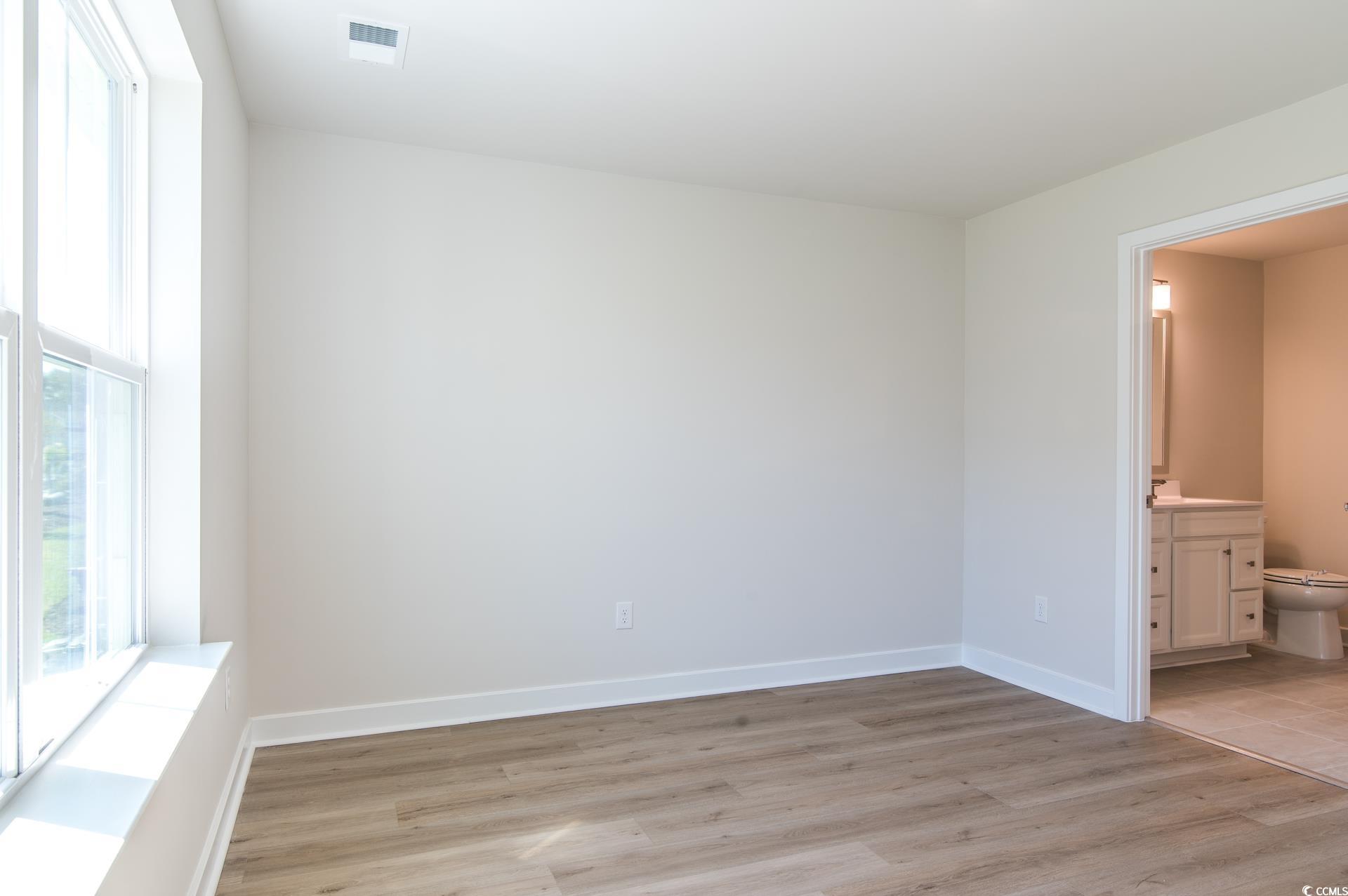 2382 Elowen Lane Longs, SC 29568 - Photo 11 of 36 Unfurnished bedroom featuring light wood finished floors, ensuite bath, and multiple windows