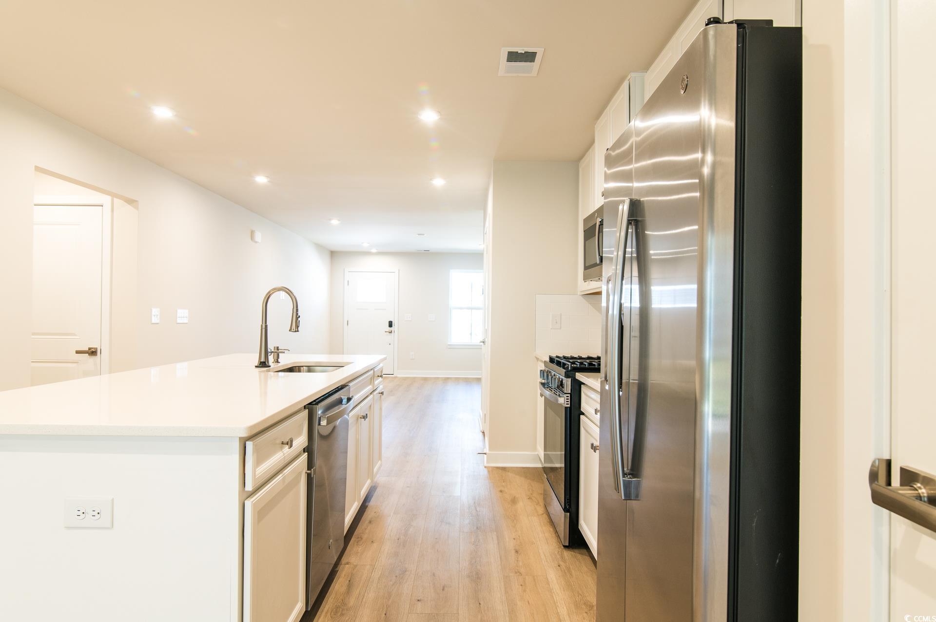 2382 Elowen Lane Longs, SC 29568 - Photo 3 of 36 Kitchen with white cabinetry, stainless steel appliances, an island with sink, recessed lighting, and light wood finished floors