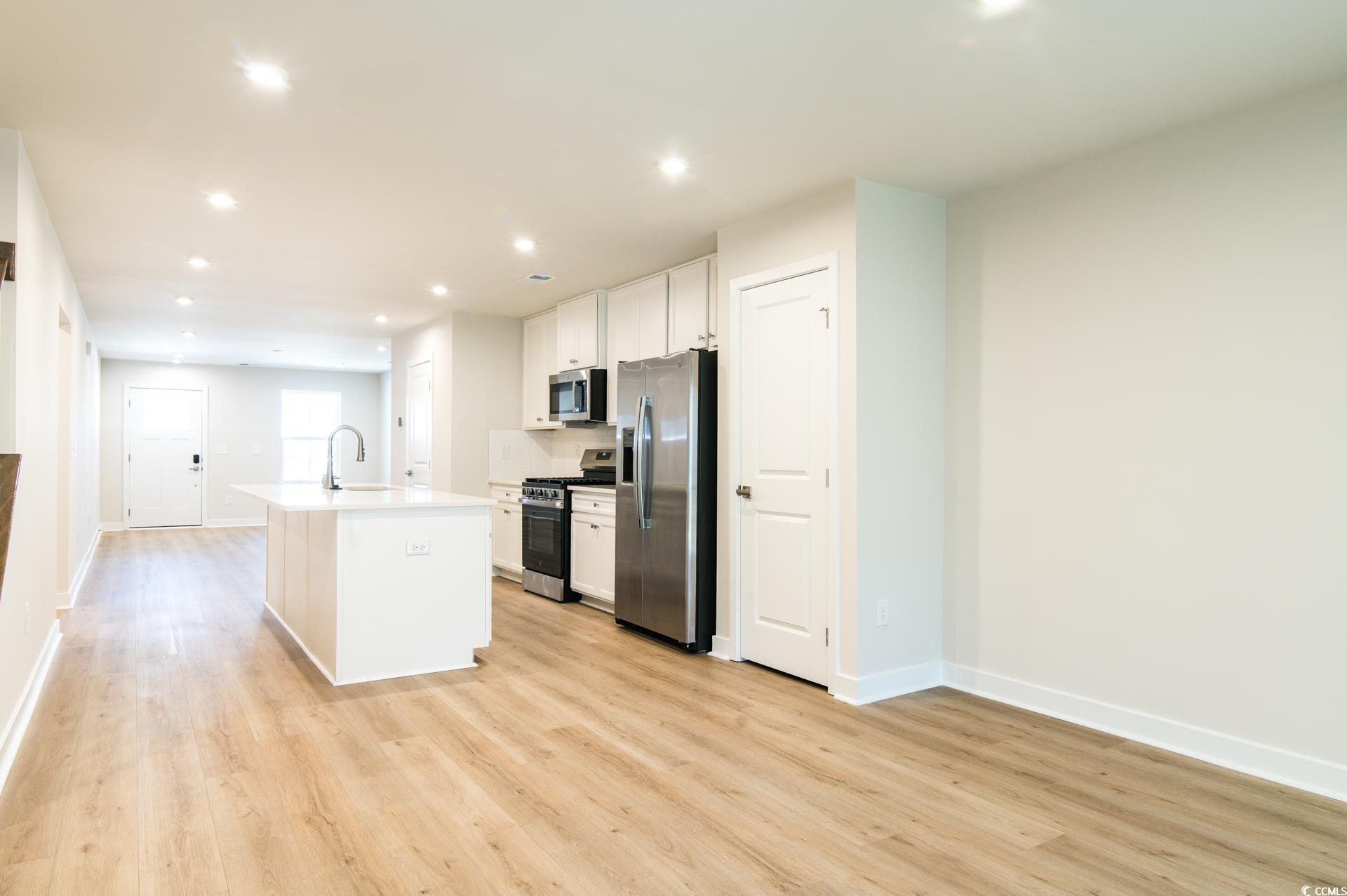2382 Elowen Lane Longs, SC 29568 - Photo 7 of 36 Kitchen with a kitchen island with sink, appliances with stainless steel finishes, white cabinets, recessed lighting, and light wood-style flooring