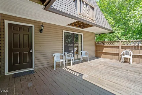 a roof deck with a table and chairs and wooden floor