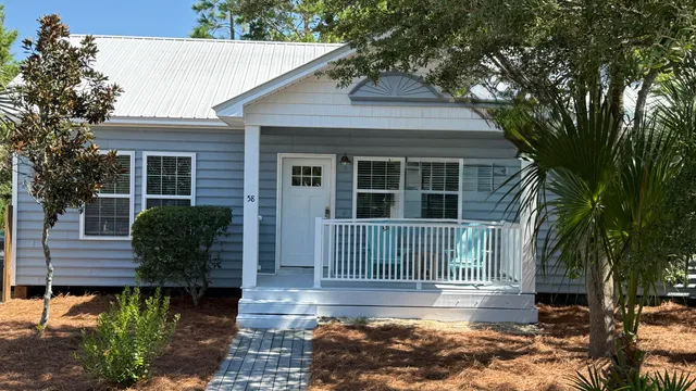 a view of a house with a small yard plants and large tree