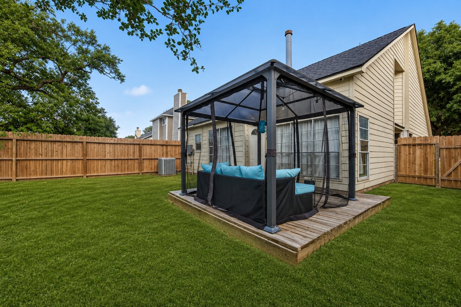 18446 North Willow Bluff Road Katy, TX 77449 - Photo 33 of 33 This photo showcases a spacious backyard with a well-maintained lawn, a wooden deck, and a cozy gazebo featuring outdoor seating. The area is enclosed by a wooden fence, providing privacy and a charming outdoor space for relaxation or entertaining.
