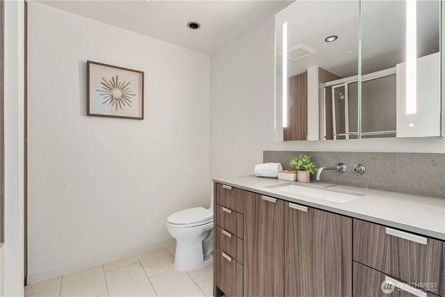 a bathroom with a granite countertop sink and a toilet