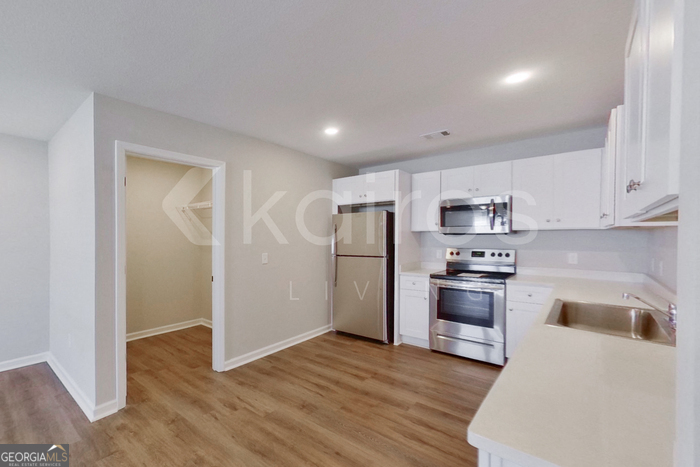 122 Cottage Grove Road Brunswick, GA 31525 - Photo 6 of 20 a kitchen with stainless steel appliances granite countertop a refrigerator a stove top oven a sink and dishwasher with wooden floor