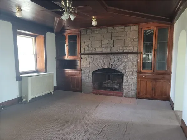 an empty room with windows and fireplace