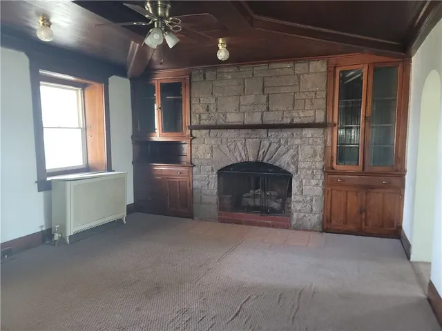an empty room with windows and fireplace