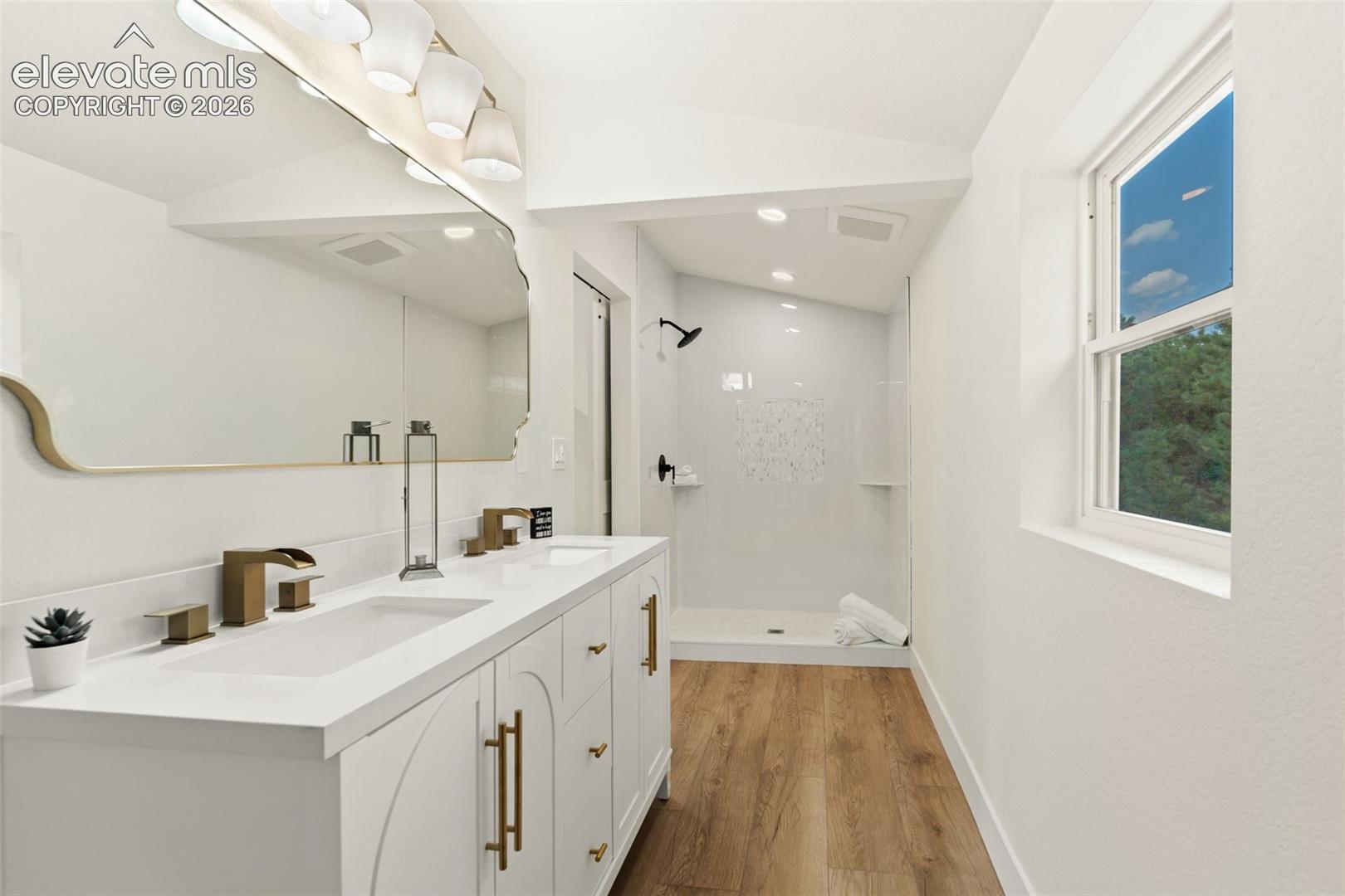 11665 Greentree Road Colorado Springs, CO 80908 - Photo 23 of 43 Bathroom with a shower stall, double vanity, light wood-style floors, and lofted ceiling