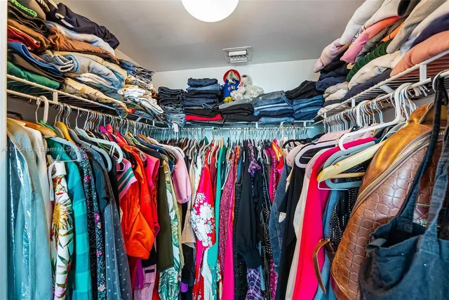 a view of walk in closet with clothes and shoes