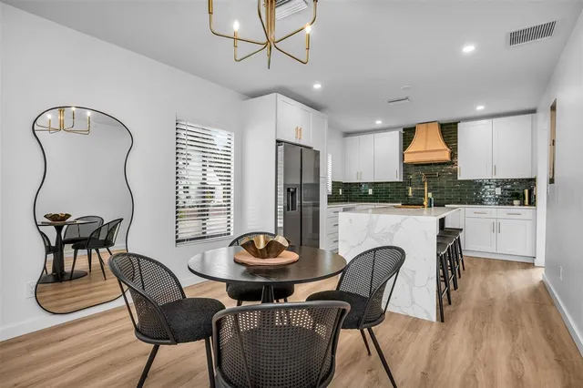 a kitchen with granite countertop a dining table chairs and a refrigerator