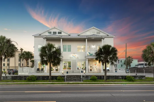 a view of a white house with a large windows and palm trees